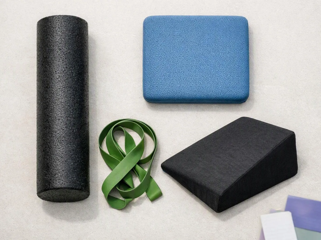 Exercise props, including foam rollers, resistance bands, and padded wedges, arranged on a light floor
